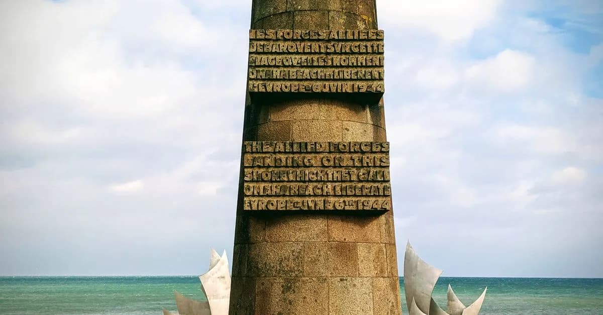 Stone monument honoring Allied forces at Normandy Beach on a clear day.