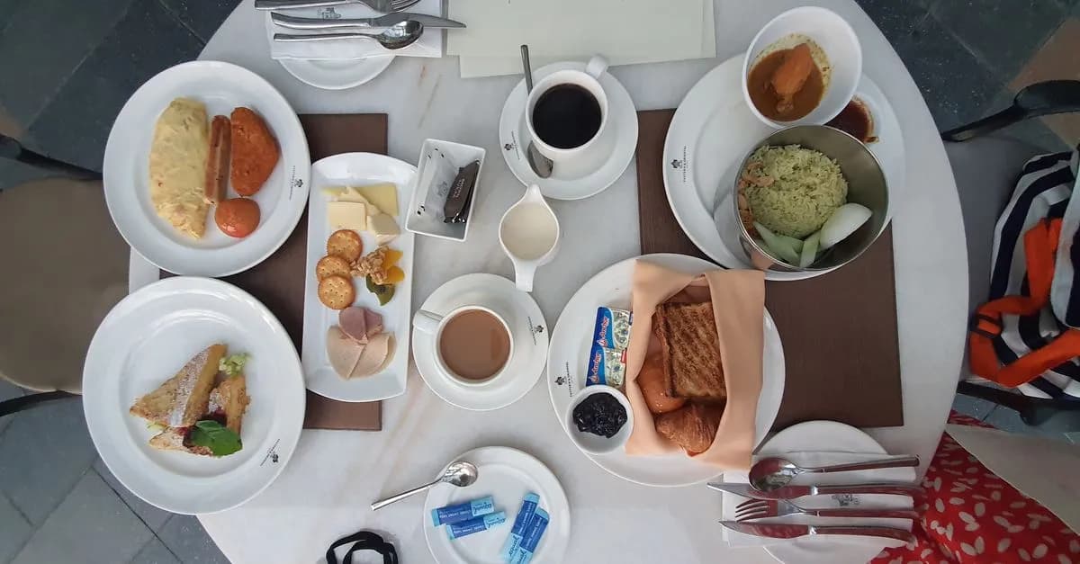 A diverse breakfast spread with coffee, toast, pastries, and more, elegantly arranged on a dining table.