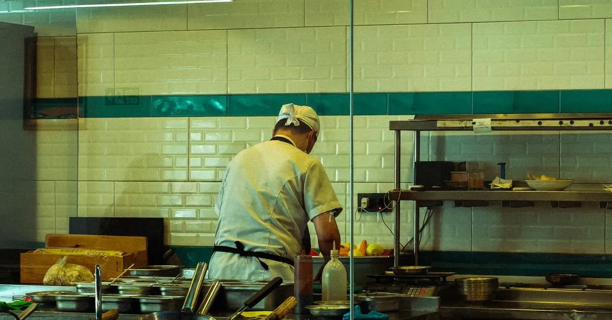 A chef in a commercial kitchen is focused on preparing fresh ingredients for a meal.