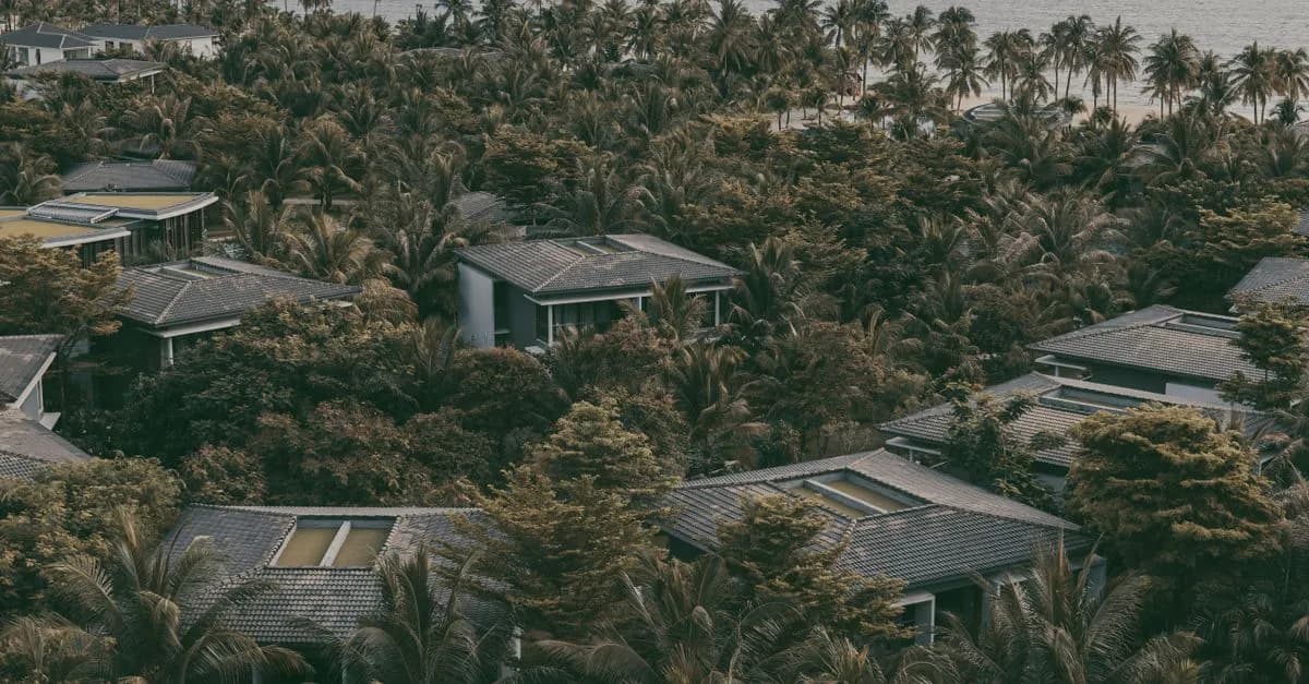 Aerial view of a tropical resort surrounded by lush palm trees near the sea in PhÚ Quáŧc, Vietnam.